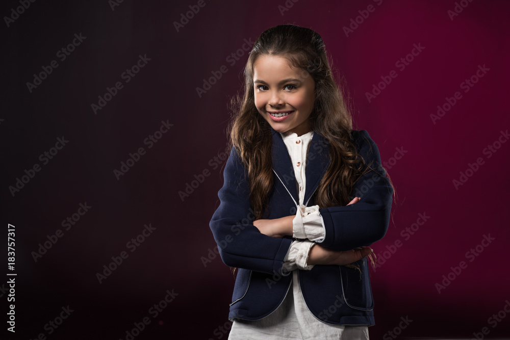smiling kid standing with crossed hands on burgundy