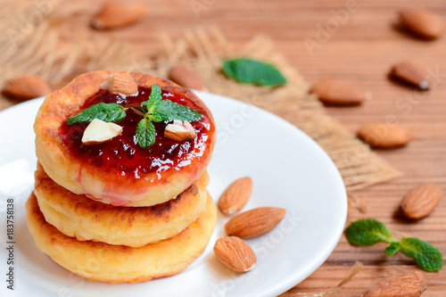 Cottage cheese pancakes with berry jam, almonds nuts and mint on a served plate. Healthy cottage cheese almond flour pancakes. Closeup