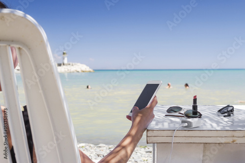 Woman using her smartphone at the beach