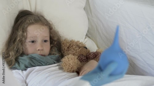 Little frightened girl looking at enema in doctor's hand, illness and healthcare
