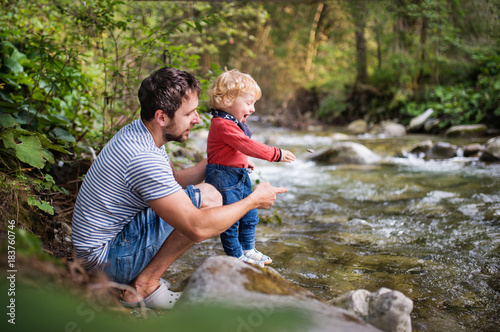 Young father with little boy at the river, summer day.