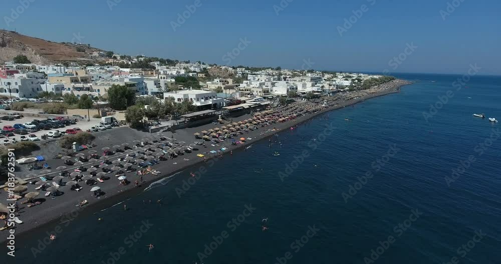 SANTORINI, GREECE – AUGUST 2016 : Aerial shot over Santorini beach on a sunny day with sea, people and cityscape in view SANTORINI, GREECE – AUGUST 2016 : Aerial shot over Santorini beach on a sunny day with sea, people and cityscape in view