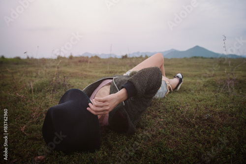 Portraif of woman lie supine on grass and wearing black hat close her face. Female sleeping outdoor for relax . Freedom concept.