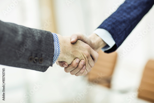 concept of a reliable partnership: a handshake of business partners on blurred light background