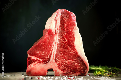 Fotografie raw t bone steak on wooden Board and black background