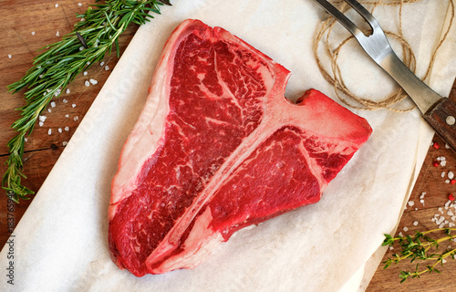 Fotografie raw porterhouse steak with herbs on a wooden Board