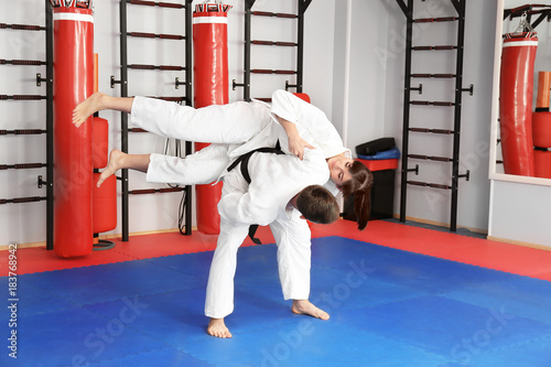 Young man and woman practicing martial arts in dojo