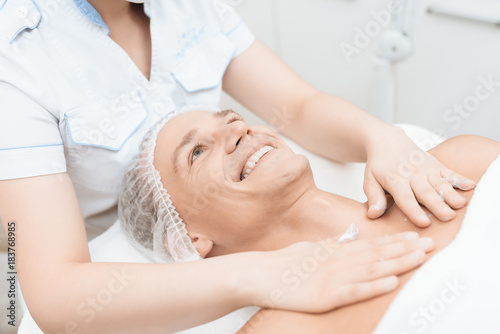 The doctor does massage and spreads cream on the face of a man who has just undergone a lacrimal hair removal procedure.