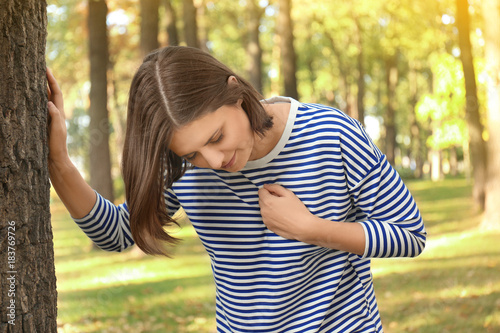 Young woman suffering from heart attack outdoors
