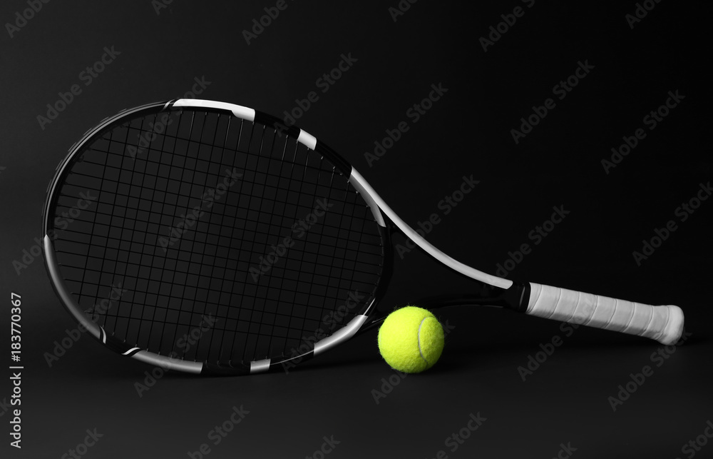 Tennis racket and ball on dark background