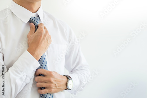 fashion and clothing concept - close up of business man in shirt dressing up and adjusting tie on neck.