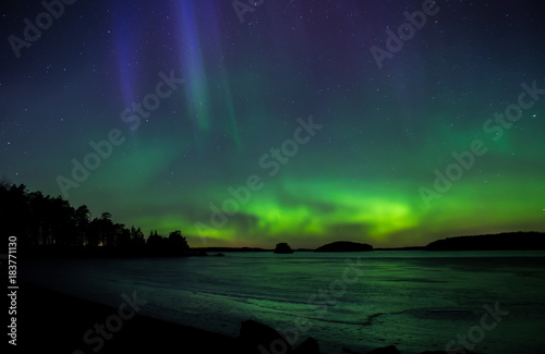 Northern lights dancing over frozen lake in Farnebofjarden national park in Sweden.