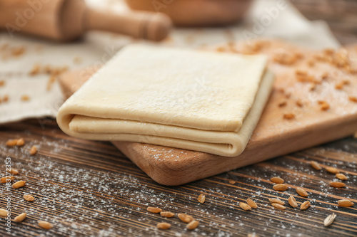 Photography Wooden board with raw flaky dough on table