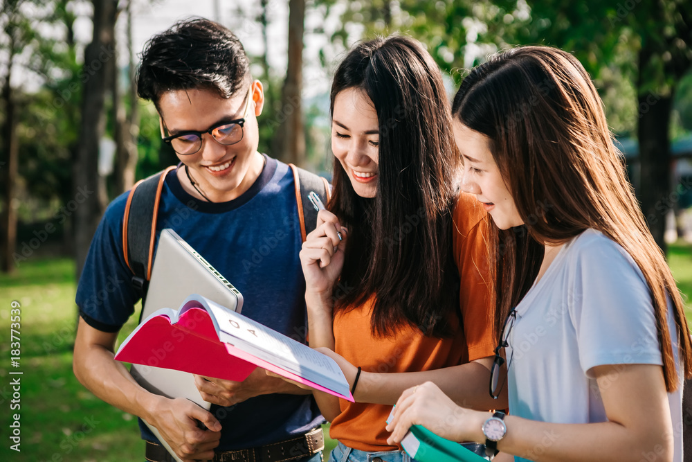 A group of young or teen Asian student in university smiling and reading the book and look at the tablet or laptop computer in summer holiday. A group of young or teen Asian student in university smiling and reading the book and look at the tablet or laptop computer in summer holiday.