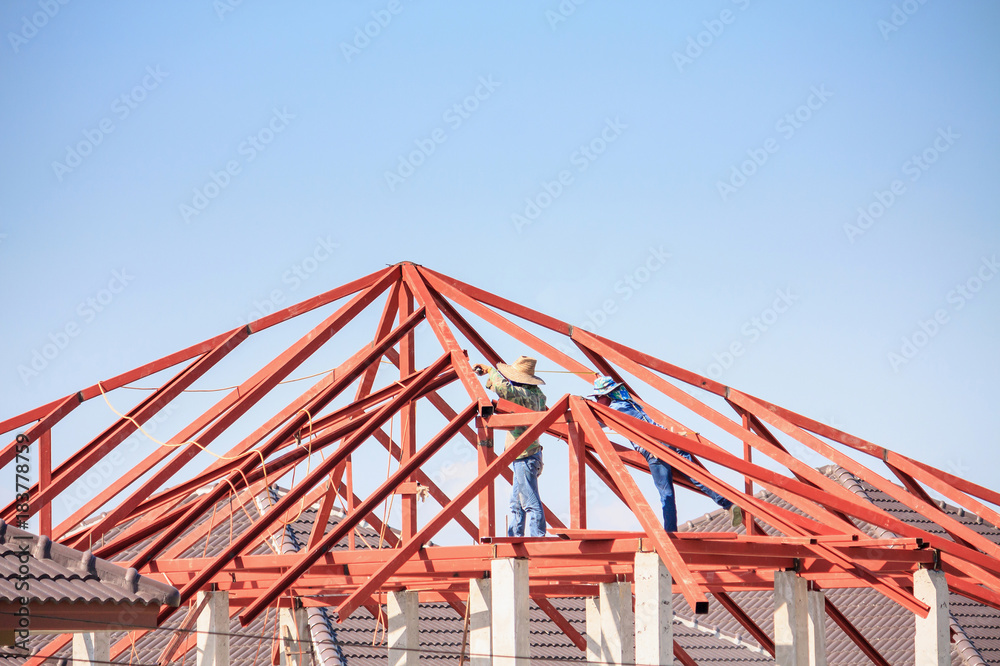 welder workers installing steel frame structure of the house roof at building construction site welder workers installing steel frame structure of the house roof at building construction site