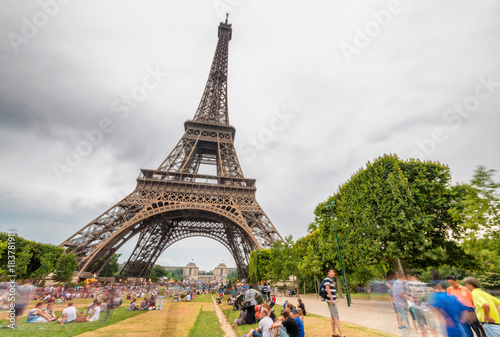 Tourists enjoy Tour Eiffel view from Champs de Mars on a cloudy day - Paris, France