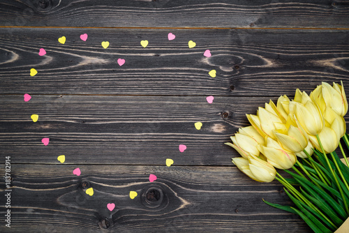 Spring background with bunch of tulip flowerswith pink heart sprinkles on wooden background. Flat lay, top view. Holiday greeting card for Valentine's Day, Woman's Day (March 8), Mother's Day, Easter photo