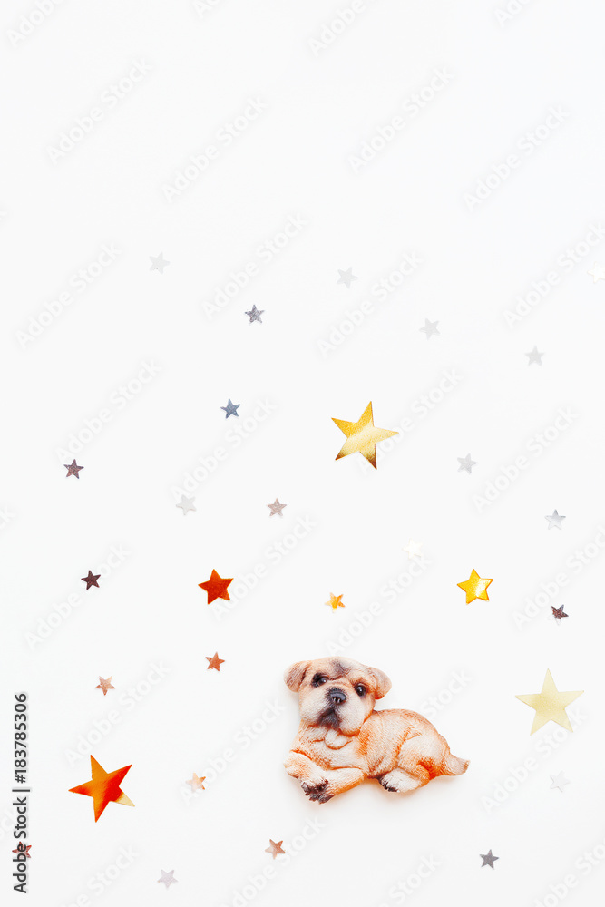 Christmas and winter holiday background with dog figure and star confetti. New Year 2018 symbol on white background with place for text.