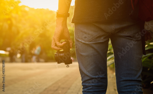 Young photographer hold camera in hand on golden light while sunset, Asian tourists travel on vacation holidays
