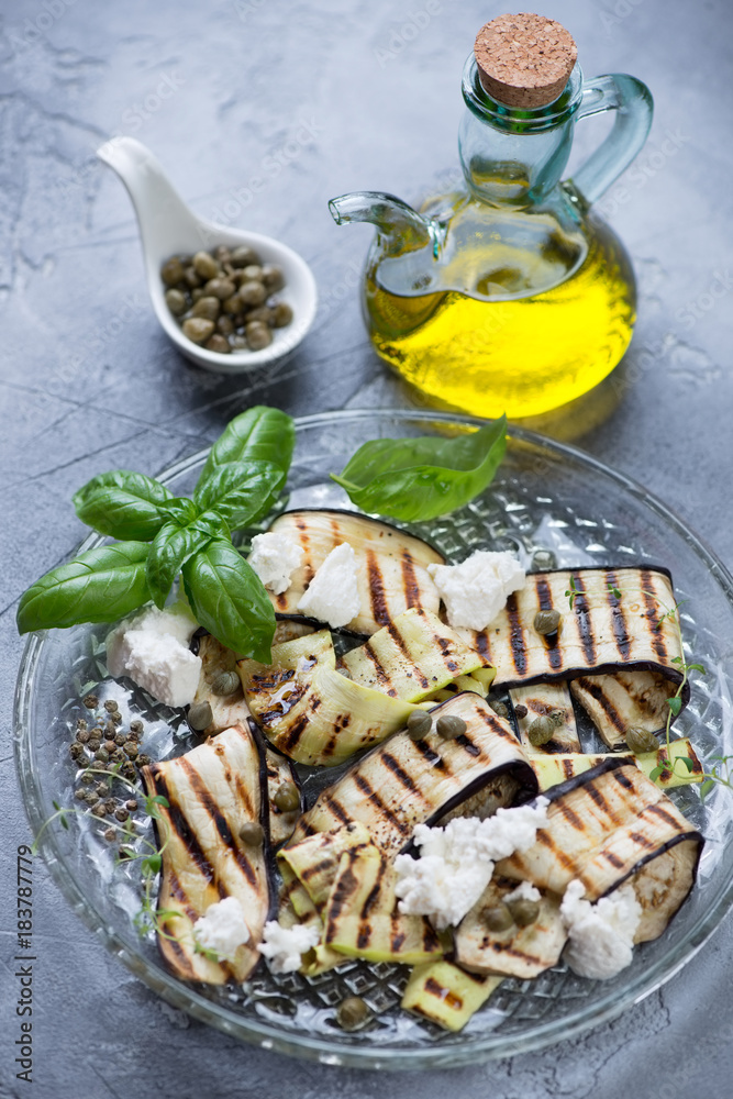 Grilled eggplants and zucchini with olive oil, capers and cheese on a