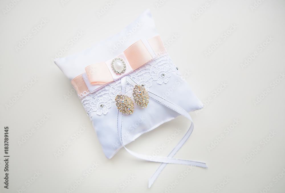 composition with wedding earrings of bride on small white lacy pillow composition with wedding earrings of bride on small white lacy pillow