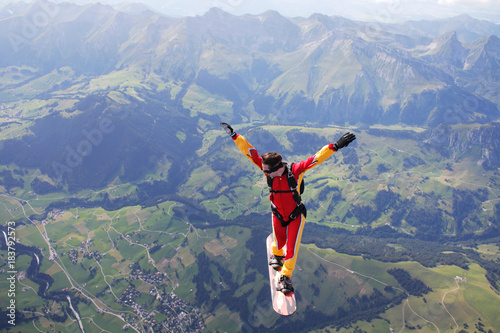 High angle view of skydiver surfing on sky board over mountains
