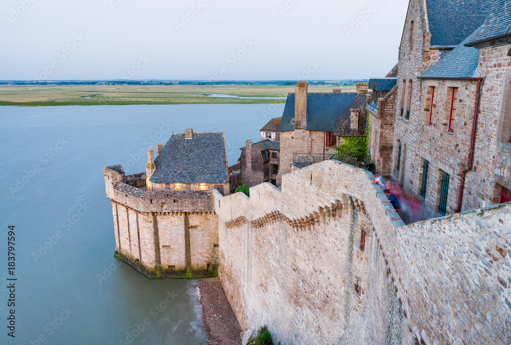 Mont Saint Michel at sunset with medieval buildings and sea - France