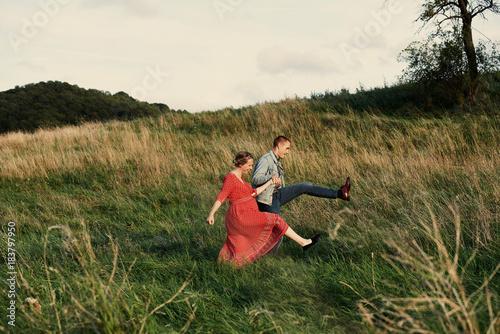Fun pregnant couple marching in field