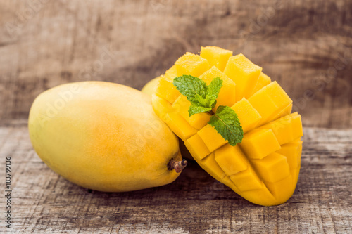 Mango fruit and mango cubes on the wooden table photo