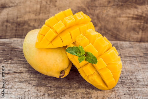 Mango fruit and mango cubes on the wooden table photo