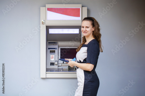 Young woman inserting a credit card to ATM