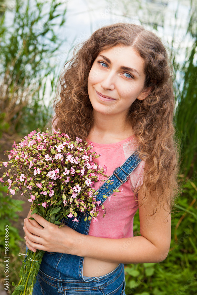 Beautiful curly woman with pink flowers outdoors Beautiful curly woman with pink flowers outdoors