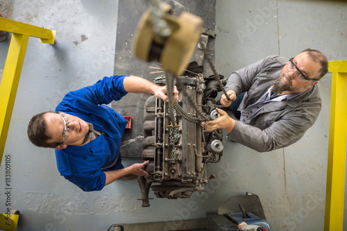 Overhead view of  car mechanics hoisting car engine in repair garage photo