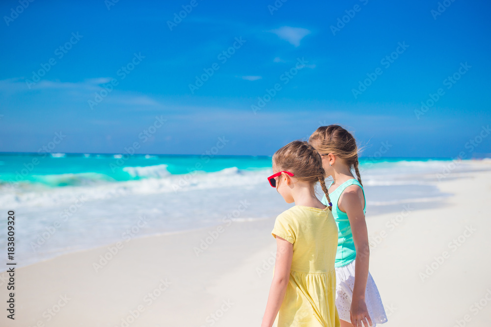 Little girls having fun at tropical beach playing together on the seashore Little girls having fun at tropical beach playing together on the seashore