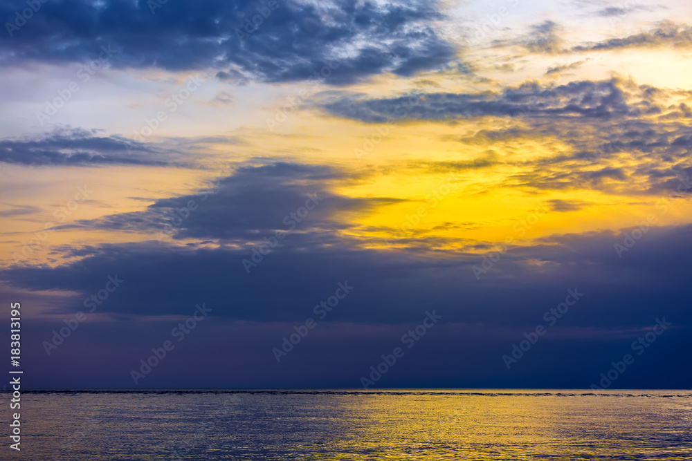 Seascape and cloudscape, orange sun light over blue clouds at dusk in the evening. Sunset on the Black Sea, Adler, Sochi, Russia.