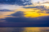 Seascape and cloudscape, orange sun light over blue clouds at dusk in the evening. Sunset on the Black Sea, Adler, Sochi, Russia.