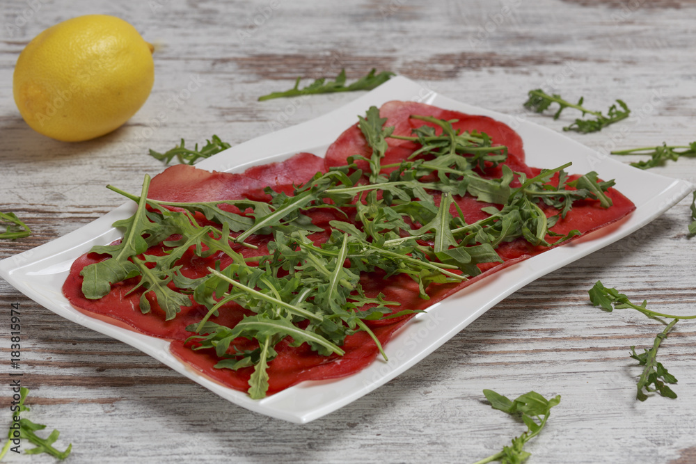 Bresaola con rucola fresca su piatto bianco