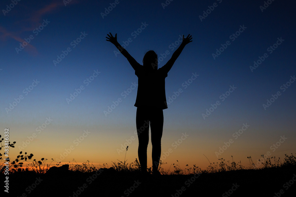 Silhouette of a standing with her hands up as the sign of happiness