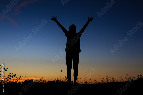 Silhouette of a standing with her hands up as the sign of happiness