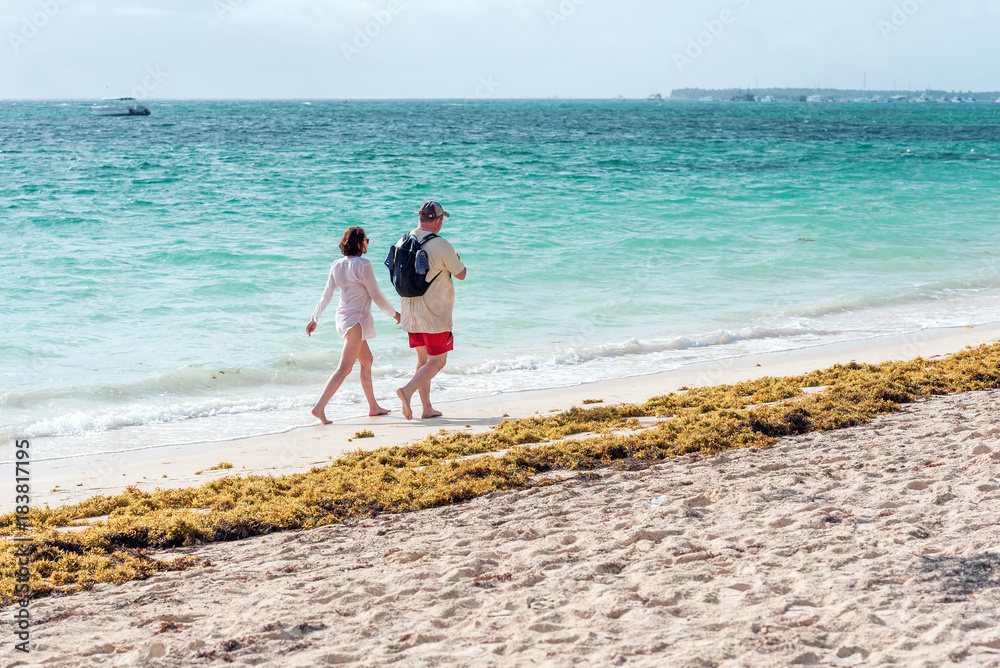Couple walking along a sandy beach in Punta Cana, La Altagracia, Dominican Republic. Copy space for text.