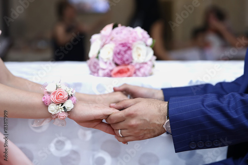The girl and the boy took each other's hands . Engageds on the background of flowers . Ring . Pink flowers