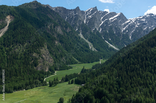Beautiful green valley with covered snow mountain peaks in the Swiss Alps