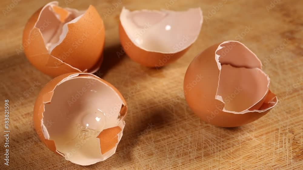 Putting some egg shells on wooden cutting board with hand Putting some egg shells on wooden cutting board with hand