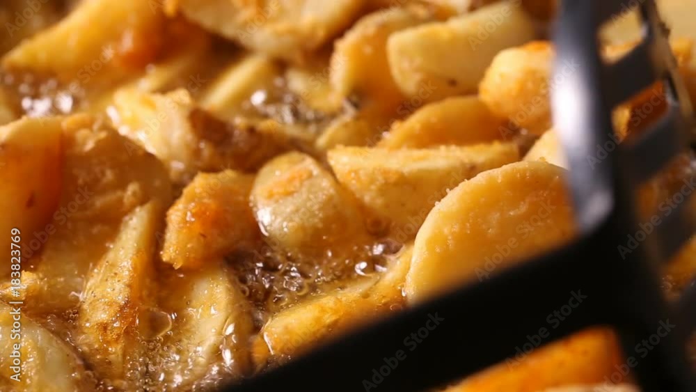 Stiring in wedges potato frying in hot boiling oil
