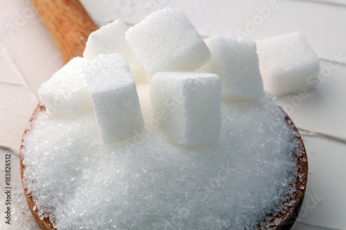 Cubes of sugar and granulated sugar with wooden spoon.