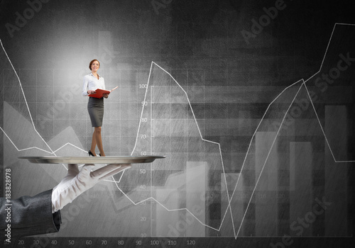 Attractive businesswoman on metal tray with red book in hands and graphs at background