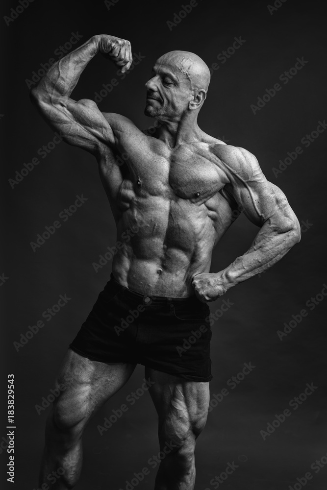 Professional strong bodybuilder athletic man posing front biceps in studio