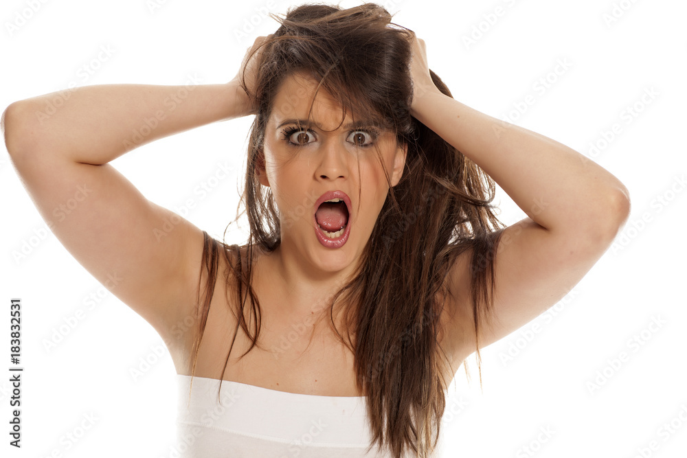 Angry young woman pulls her hair on white background Angry young woman pulls her hair on white background