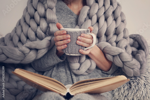 Cozy Woman covered with warm soft merino wool blanket reading a book. Relax, comfort lifestyle. photo