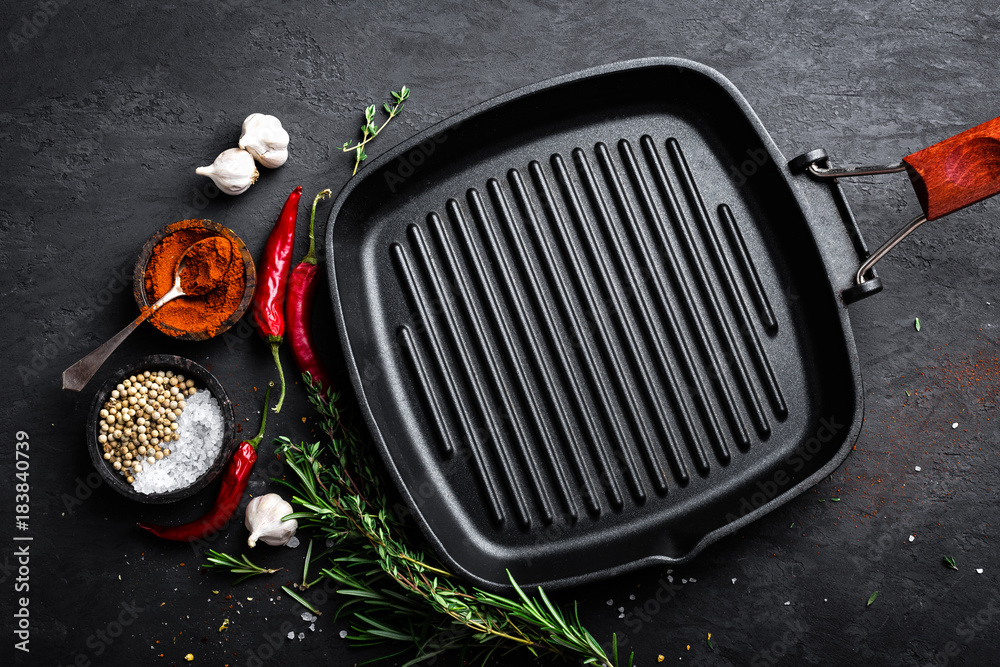 Empty cast-iron grill pan with ingredients for cooking on black background, top view - obrazy, fototapety, plakaty 